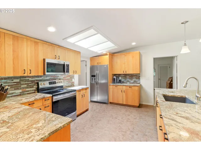 a kitchen with stainless steel appliances kitchen island granite countertop a stove and a sink
