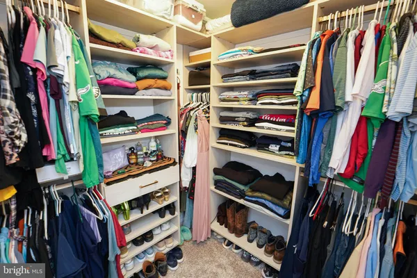 a view of walk in closet with clothes and shoes
