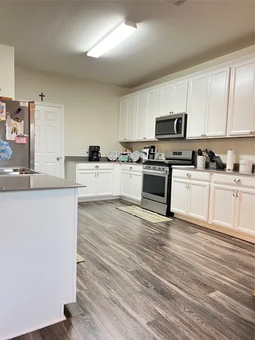 a kitchen with granite countertop a stove top oven a sink dishwasher and a refrigerator