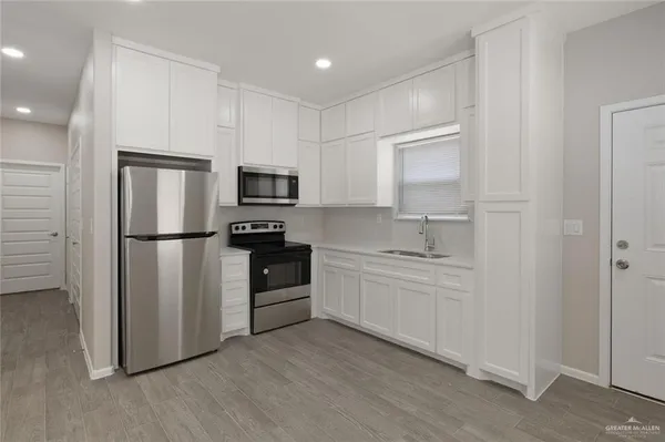 a kitchen with granite countertop a refrigerator stove and microwave
