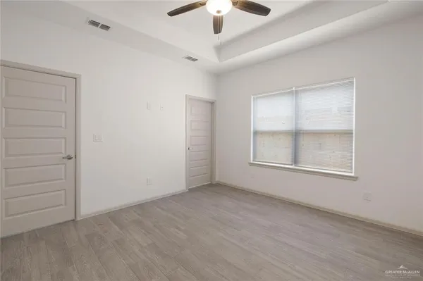an empty room with ceiling fan and window