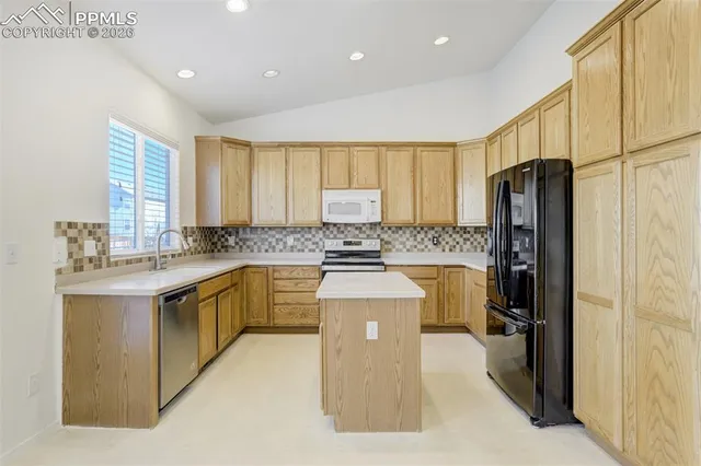 a kitchen with stainless steel appliances granite countertop a refrigerator a stove and a sink
