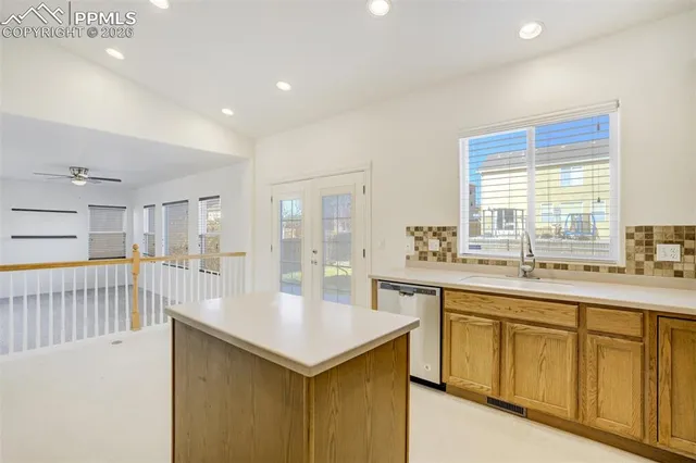 an empty room with chandelier fan and windows