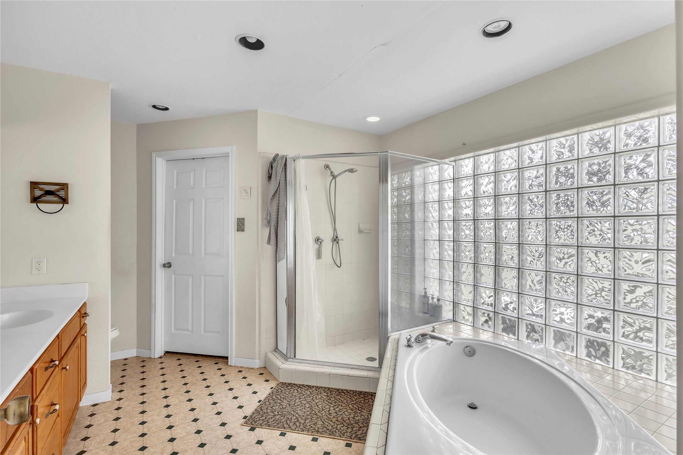 1080 League Line Road Paige, TX 78659 - Photo 16 of 39 Glass block windows filter natural light into a bathroom featuring a corner shower and soaking tub.