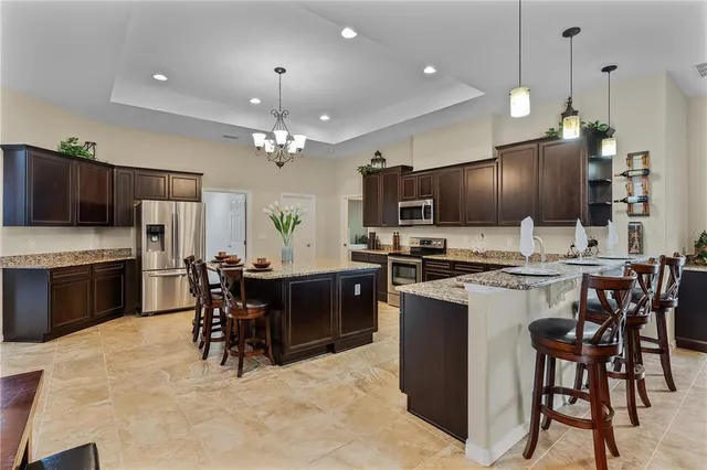 a kitchen with stainless steel appliances kitchen island granite countertop a table chairs and a refrigerator