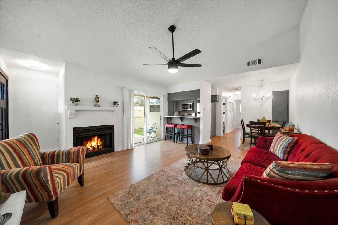 Side A- Bright family room with striped chairs and a vibrant fireplace.