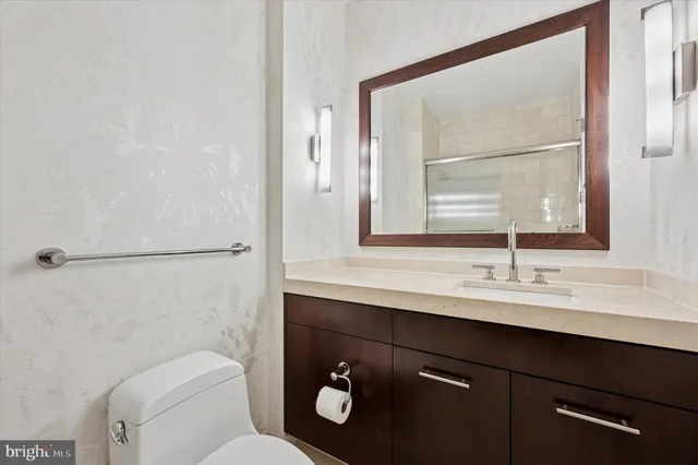 a bathroom with a toilet a sink a mirror and a window