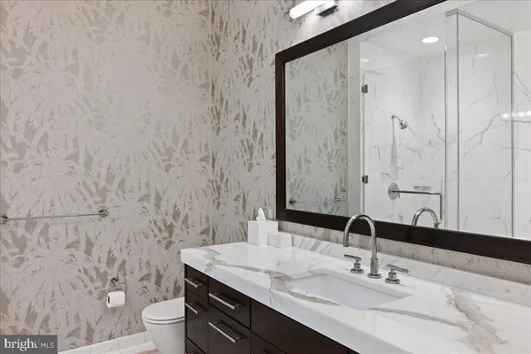 a bathroom with a granite countertop sink a toilet and a mirror