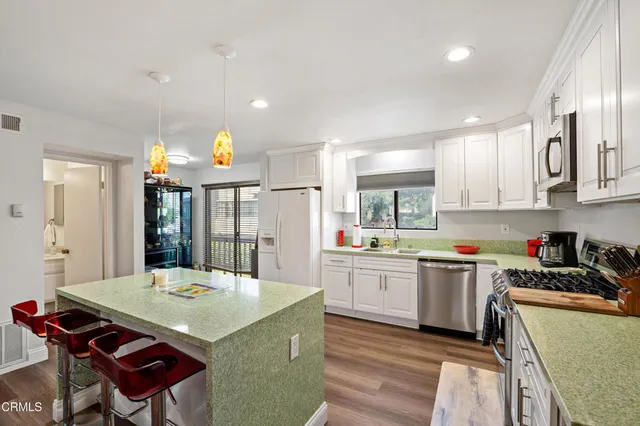 a kitchen with stainless steel appliances kitchen island granite countertop a sink a stove a dining table and chairs