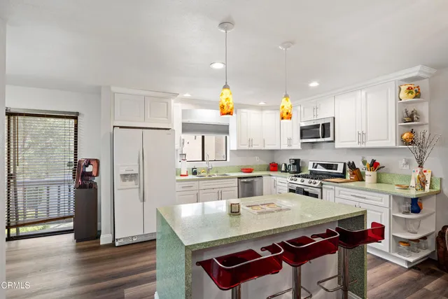 a kitchen with a refrigerator a stove a sink and dishwasher with wooden floor
