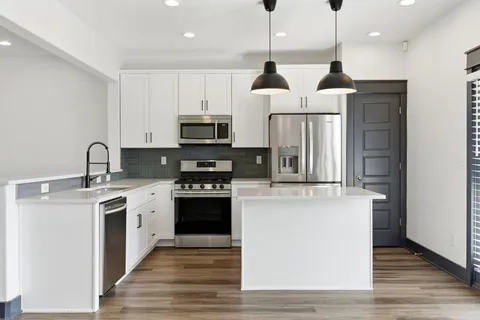a kitchen with stainless steel appliances a refrigerator a stove a sink and a center island