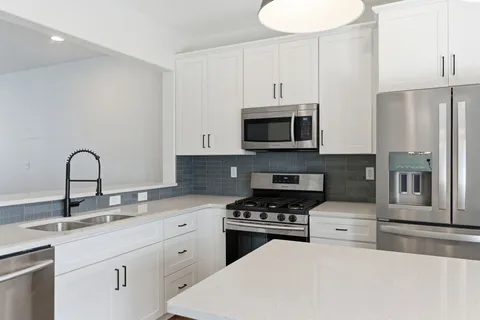 a kitchen with granite countertop a sink stainless steel appliances and white cabinets