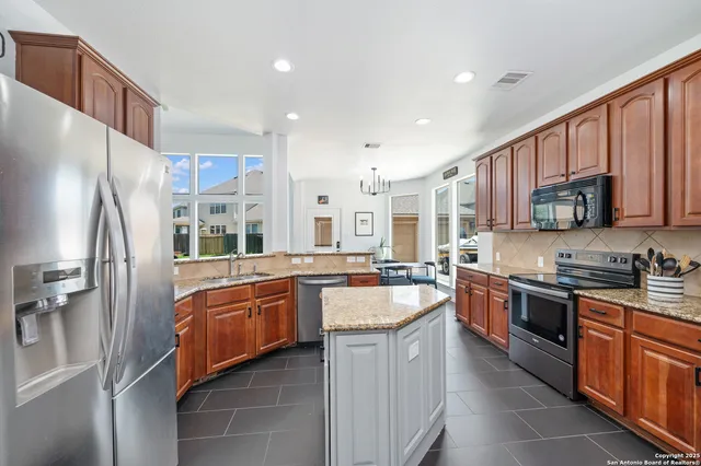 a large kitchen with stainless steel appliances granite countertop a stove a sink dishwasher a refrigerator and a microwave