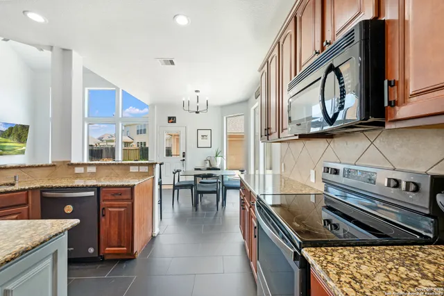 a kitchen with stainless steel appliances granite countertop a stove a sink and a microwave
