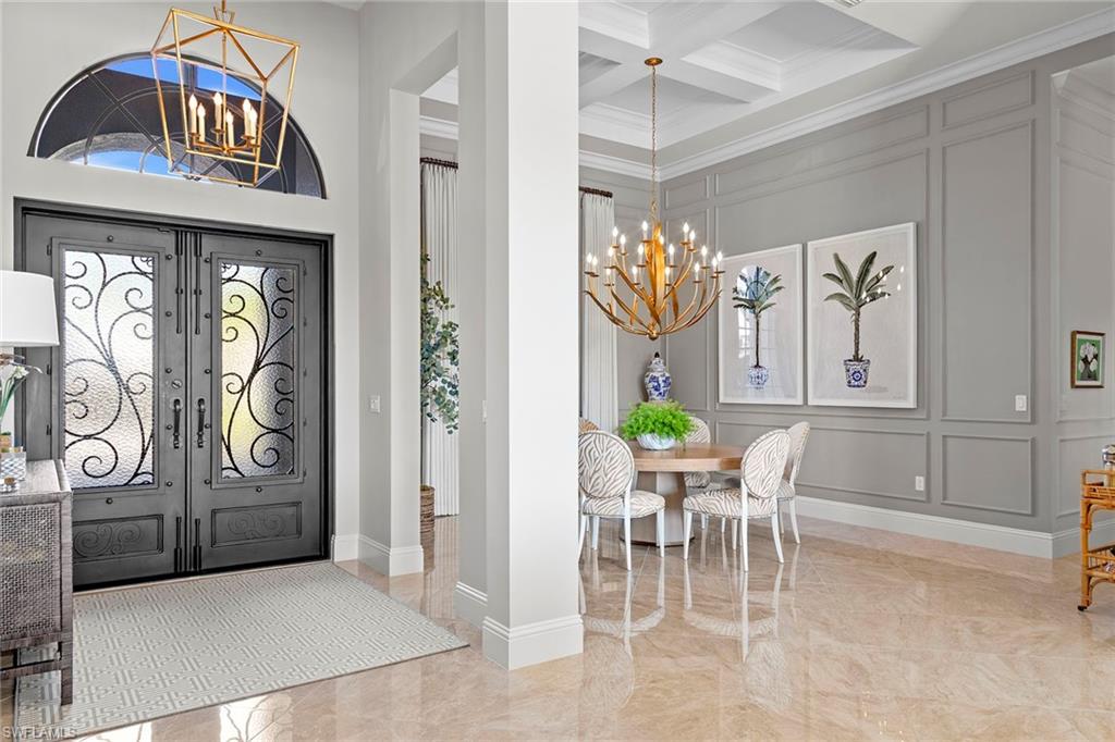 4170 Cortland Way Naples, FL 34119 - Photo 5 of 41 Foyer entrance featuring a chandelier, a decorative wall, light marble finish floors, coffered ceiling, and ornamental molding