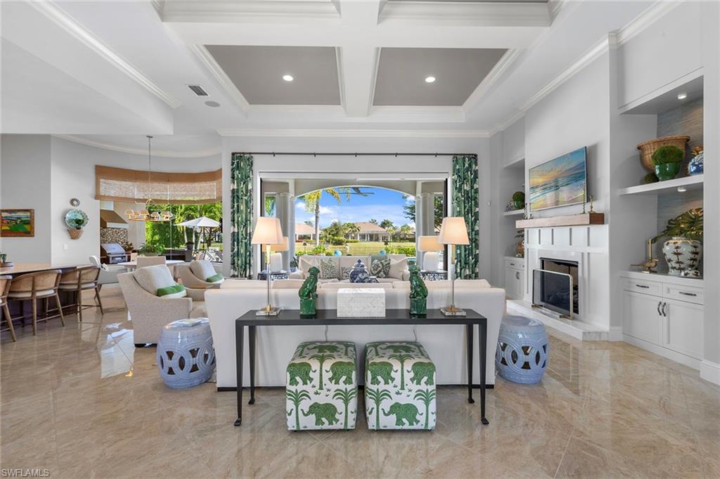 4170 Cortland Way Naples, FL 34119 - Photo 8 of 41 Living room with coffered ceiling, beamed ceiling, a fireplace with raised hearth, built in features, and ornamental molding