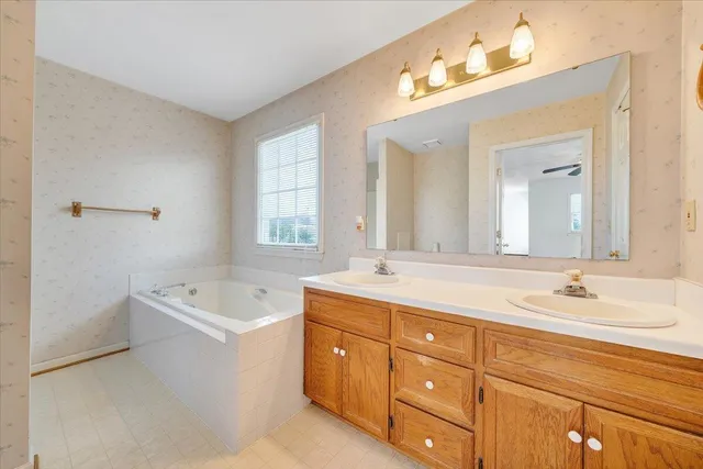 a spacious bathroom with double vanity sink a mirror a bathtub and