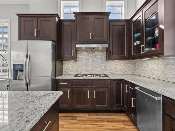 a kitchen with a refrigerator a stove a sink and dishwasher with wooden floor