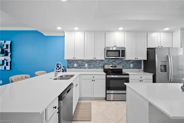 a kitchen with a sink a stove a refrigerator and white cabinets