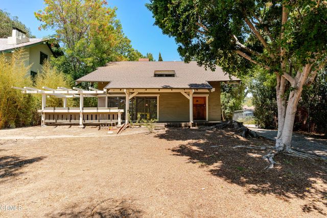 a view of a white house with a large tree and yard