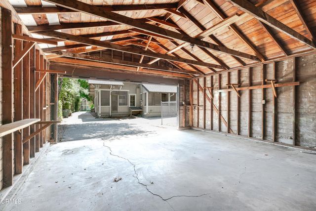 a view of a white house with large tree and wooden fence