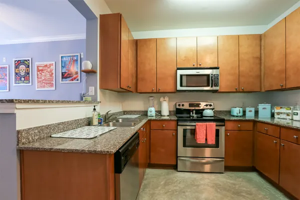 a kitchen with stainless steel appliances granite countertop a stove top oven a sink dishwasher and microwave with wooden cabinets