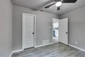 an empty room with wooden floor chandelier fan and entryway