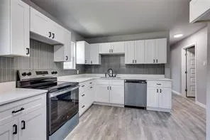 a kitchen with granite countertop cabinets stainless steel appliances and a wooden floor