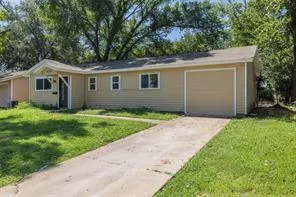 a view of a house with a yard plants and large tree
