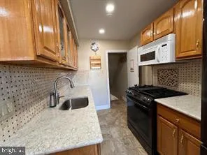 a kitchen with granite countertop a sink a stove and cabinets