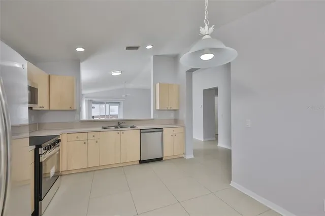 a large kitchen with a sink and dishwasher a stove top oven with wooden floor