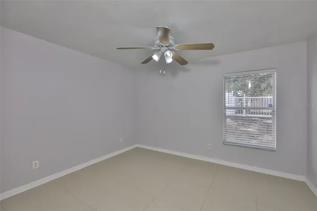 an empty room with a window and ceiling fan