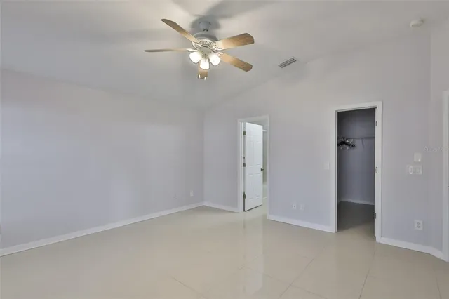 an empty room with a chandelier fan and closet area