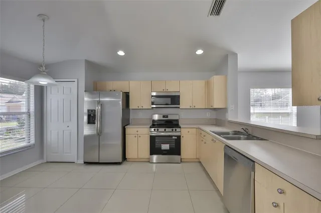 a kitchen with stainless steel appliances granite countertop a refrigerator a sink and a stove