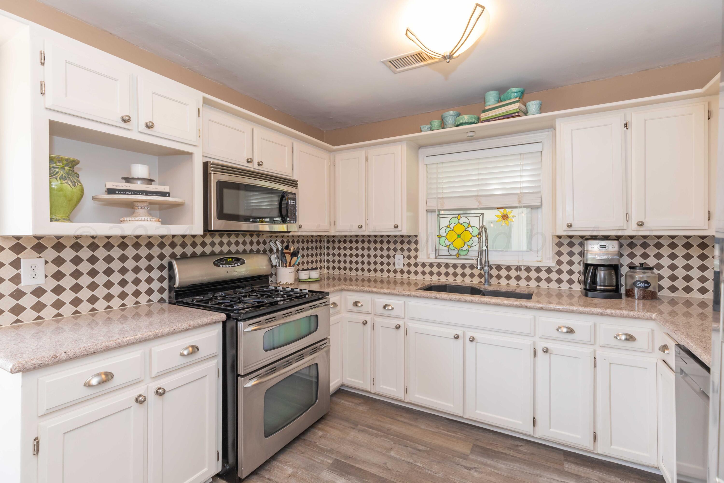 1007 South Alabama Street Amarillo, TX 79102 - Photo 13 of 55 a kitchen with granite countertop a sink white cabinets and appliances