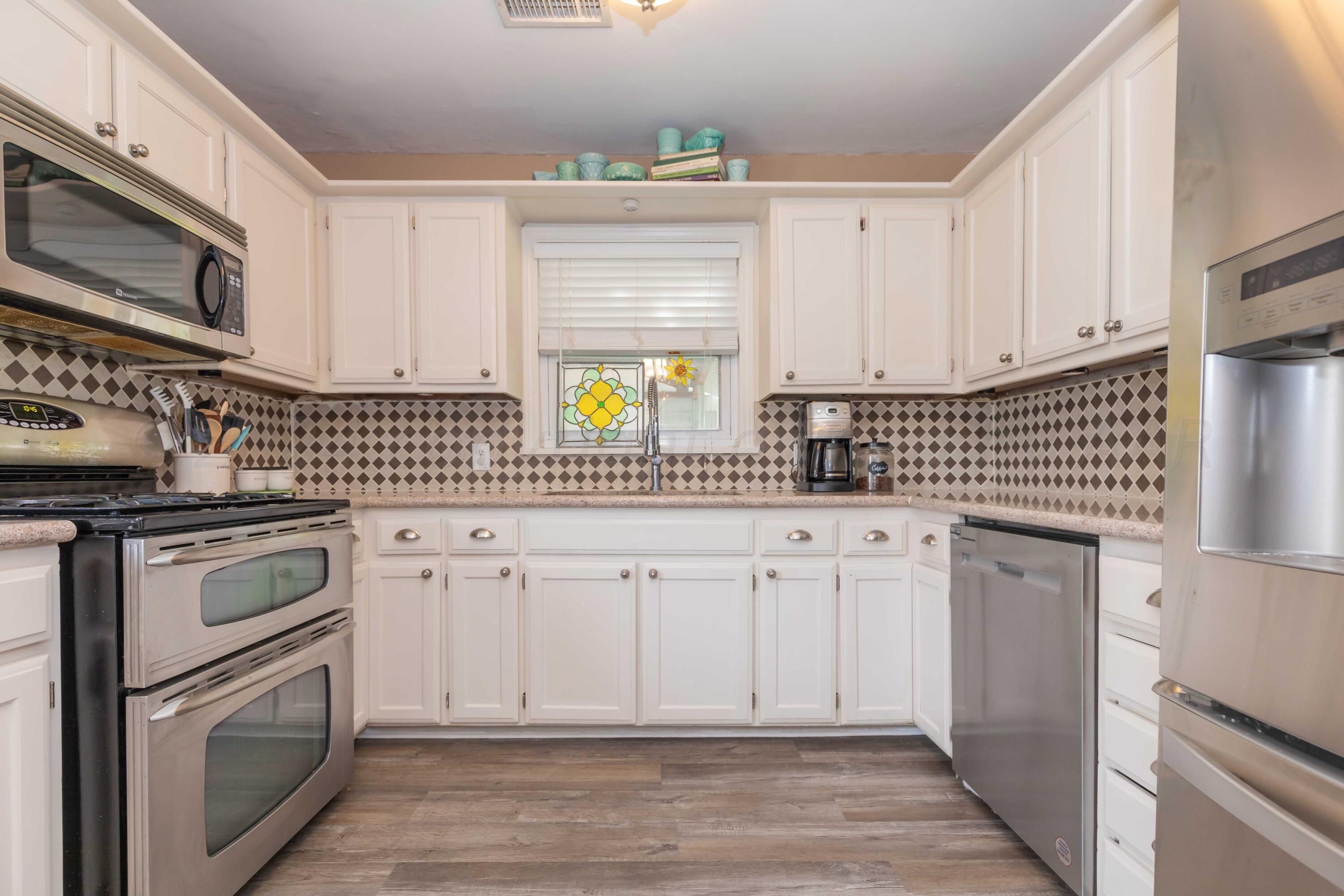 1007 South Alabama Street Amarillo, TX 79102 - Photo 15 of 55 a kitchen with stainless steel appliances white cabinets and a stove a refrigerator with wooden floor