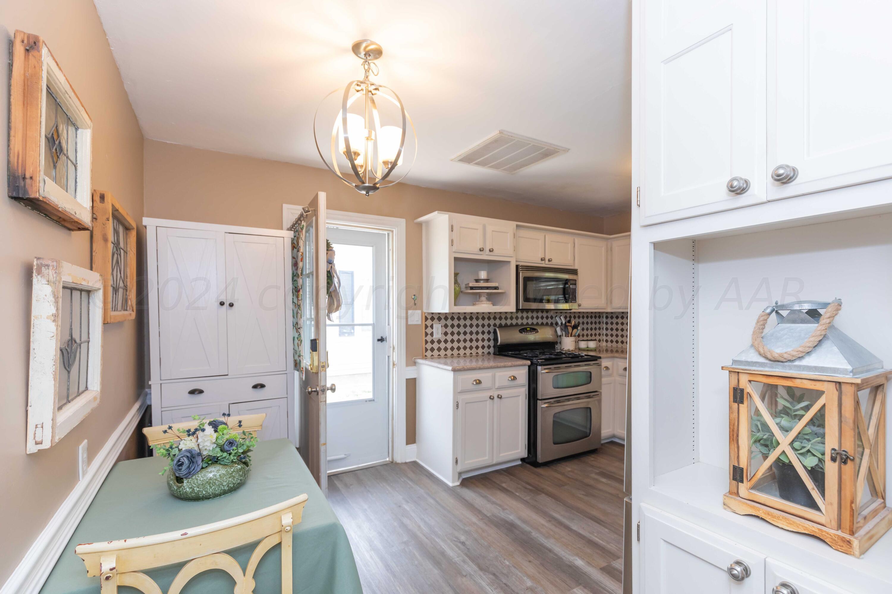 1007 South Alabama Street Amarillo, TX 79102 - Photo 17 of 55 a kitchen with stainless steel appliances granite countertop a stove a refrigerator a sink a microwave oven with cabinets and wooden floor