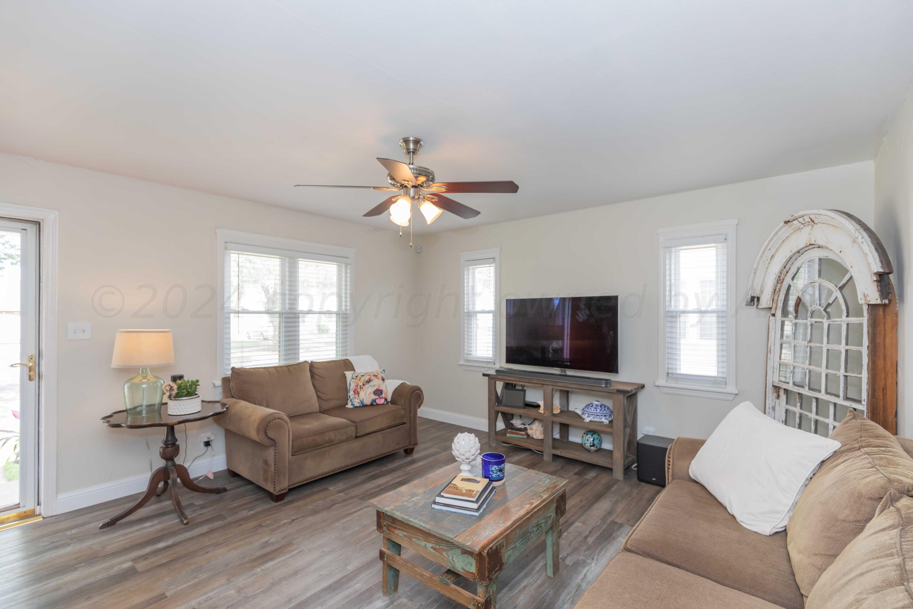 1007 South Alabama Street Amarillo, TX 79102 - Photo 10 of 55 a living room with furniture a chandelier a window and a flat screen tv