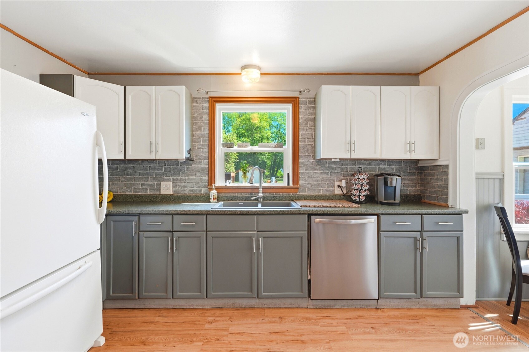 21716 State Rte 530 Northeast Arlington, WA 98223 - Photo 16 of 38 a kitchen with stainless steel appliances granite countertop a coffee maker a sink a refrigerator and white cabinets with wooden floor