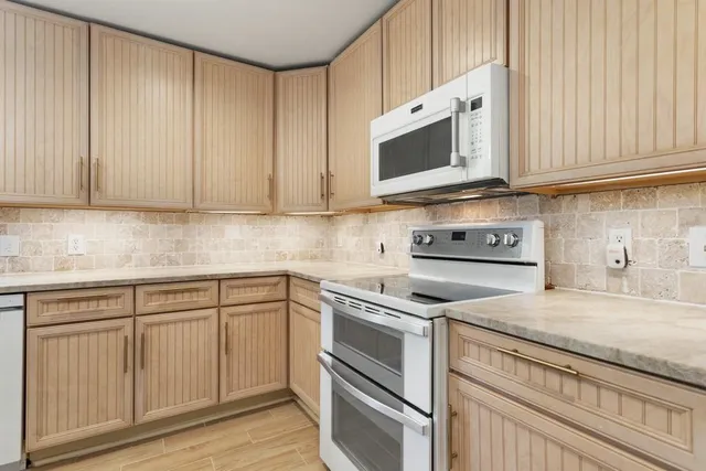 a kitchen with stainless steel appliances granite countertop white cabinets and a stove top oven