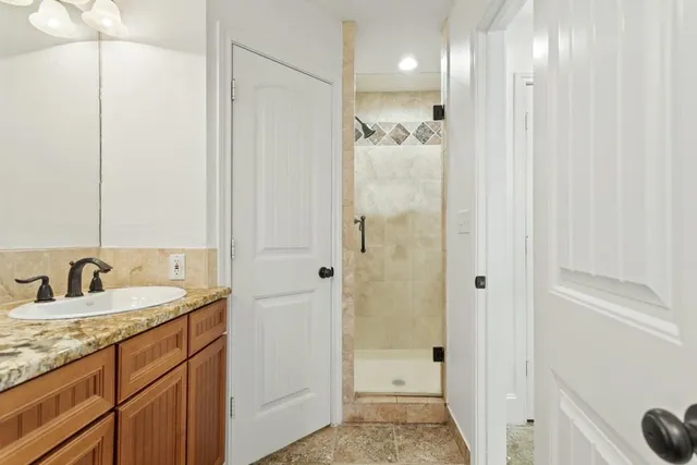 a bathroom with a granite countertop sink two mirror and shower