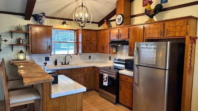 a kitchen with stainless steel appliances granite countertop a refrigerator a sink dishwasher a stove and a dining table with wooden floor