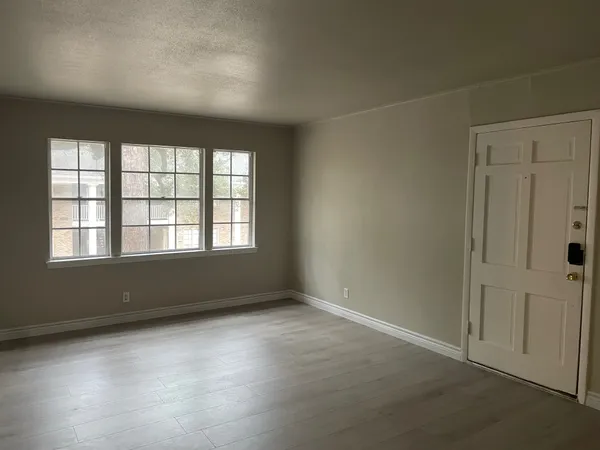 an empty room with wooden floor and windows