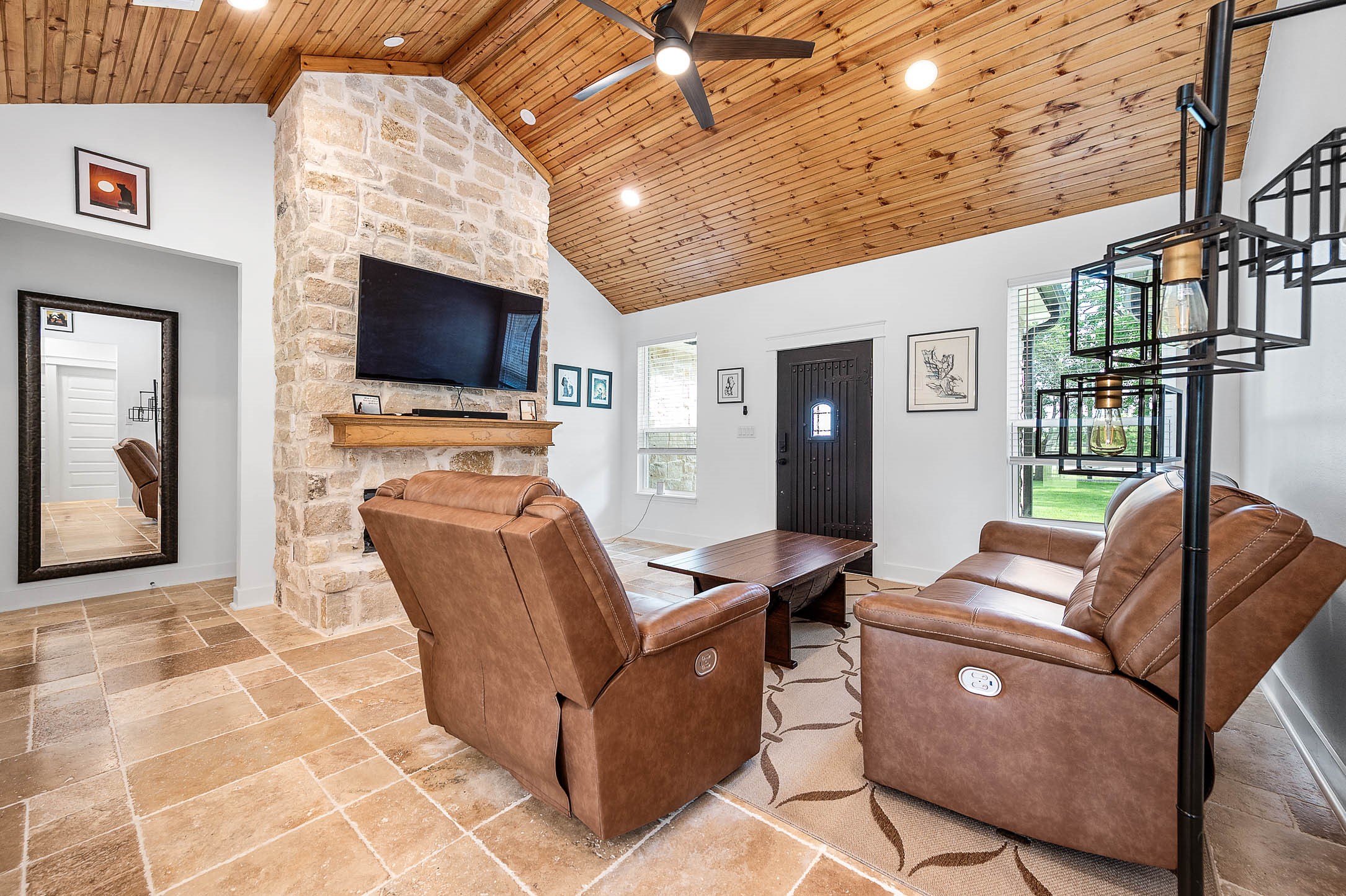 8032 Short Road Needville, TX 77461 - Photo 8 of 50 Designed for comfort and everyday living, this inviting space features soaring wood ceilings, a floor-to-ceiling stone fireplace, and large windows that bring in abundant natural light. The open layout and warm finishes make the room feel both spacious and welcoming.