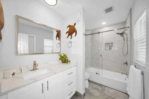 a bathroom with a granite countertop sink a toilet and shower