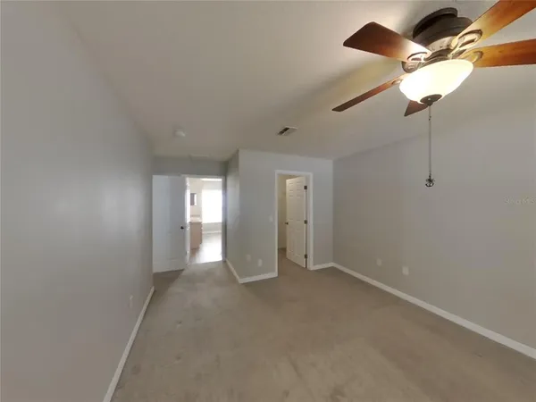 a view of an empty room and a chandelier fan