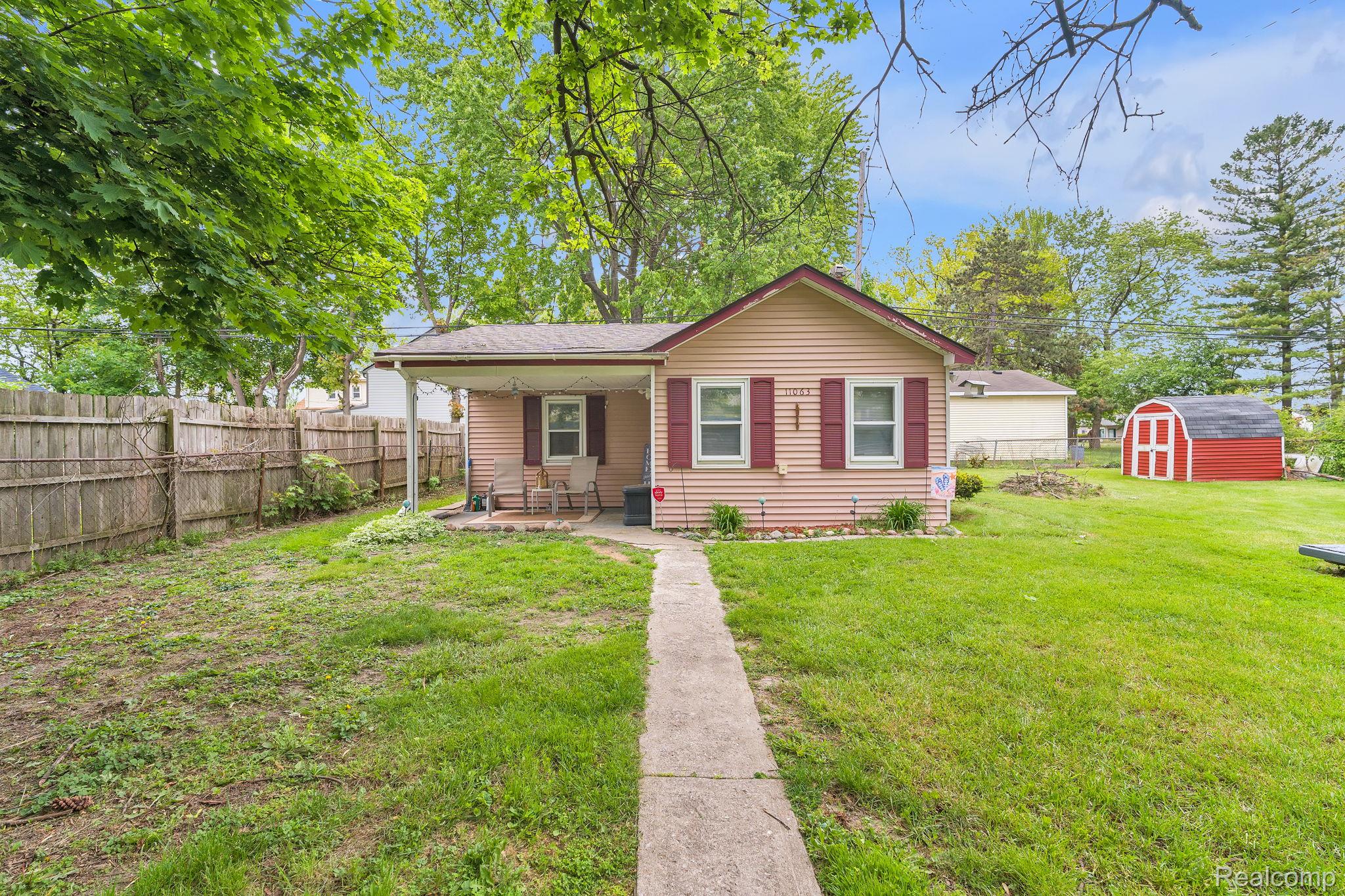 11063 Jackson Street Taylor, MI 48180 - Photo 2 of 27 Spacious rear yard featuring a concrete walkway, mature trees, and a red storage shed