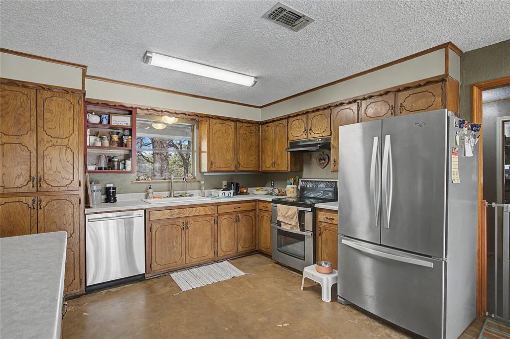 243 County Road 3851 Poolville, TX 76487 - Photo 12 of 34 a kitchen with stainless steel appliances granite countertop a refrigerator sink and stove