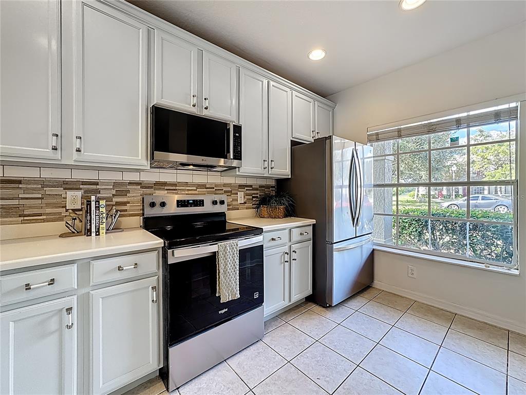 10300 Manderley Way, Unit 119 Orlando, FL 32829 - Photo 5 of 42 a kitchen with stainless steel appliances granite countertop a stove a refrigerator and a microwave