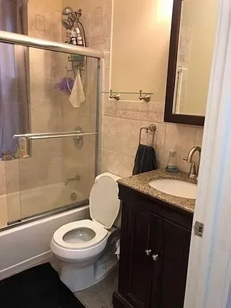 a bathroom with a granite countertop toilet sink and mirror